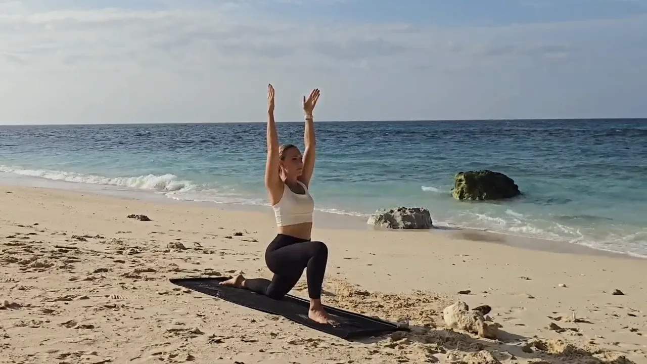 Jen in a deep Crescent Lunge with arms raised by a fireplace