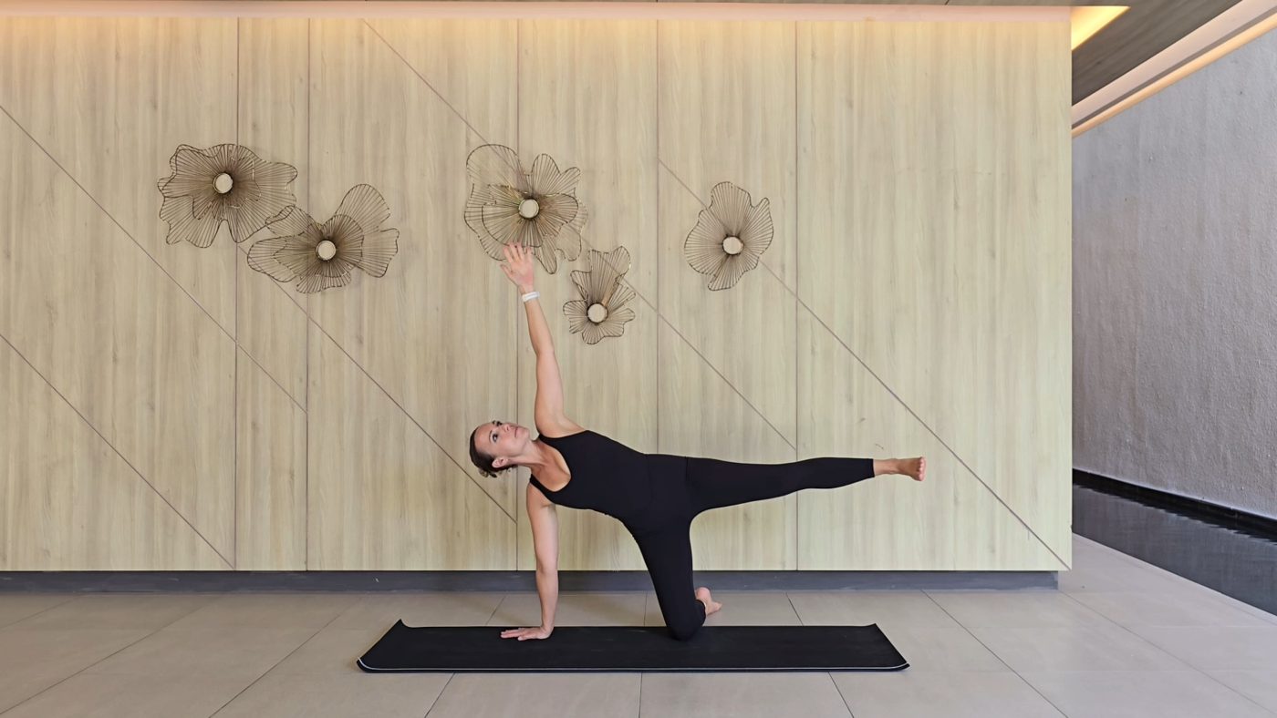 Jen in Warrior One pose in a studio with floral wall decor